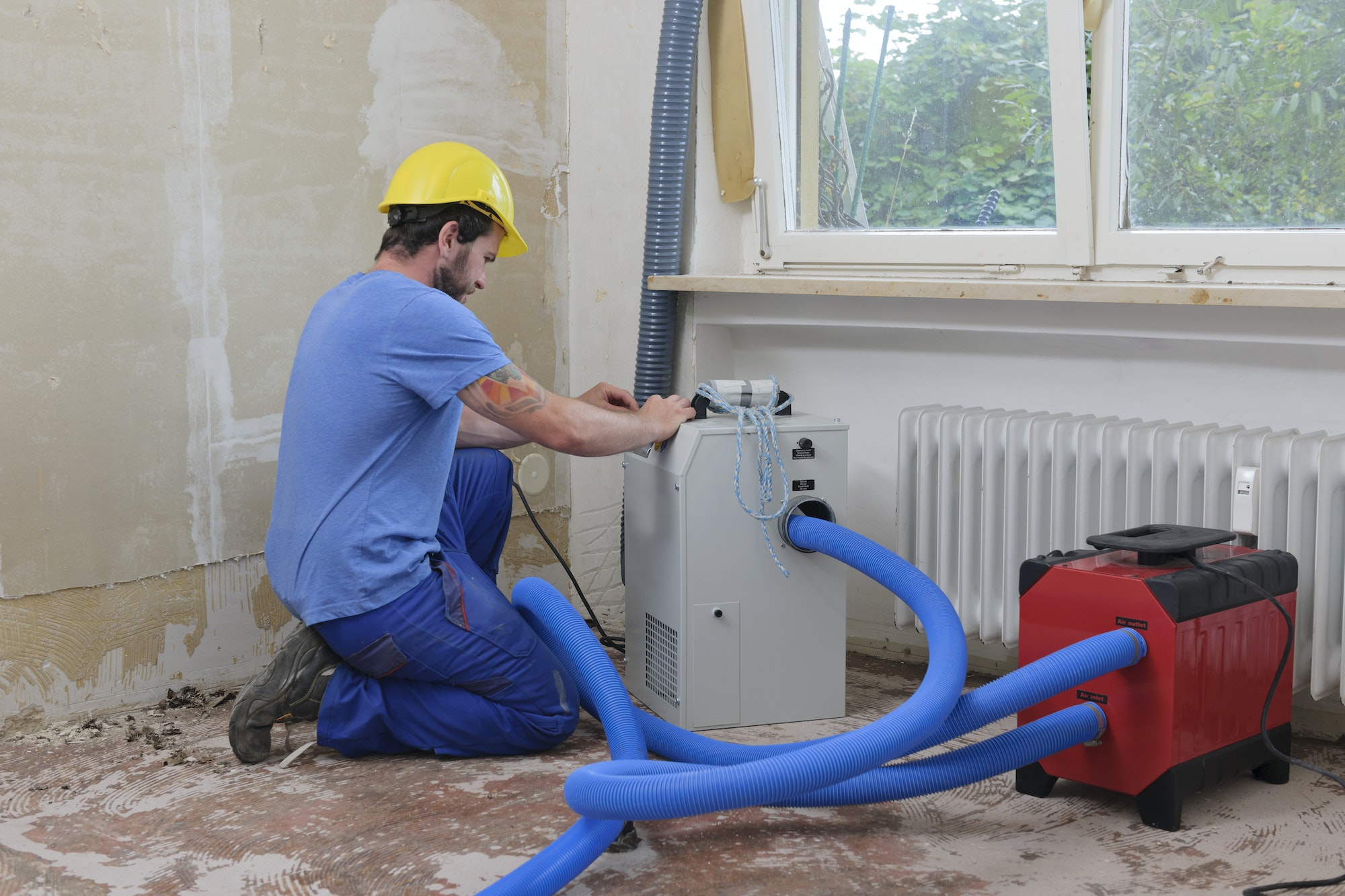Worker adjusting dehumidifier in an apartment which is damaged by flooding